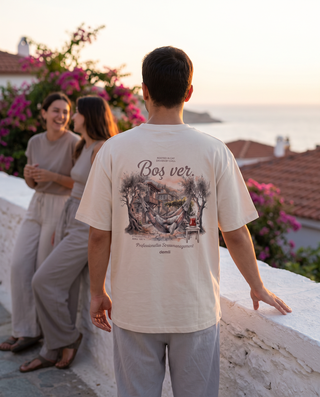 Person im demli Boş ver. Shirt in Sand von hinten auf einer Dachterrasse bei Sonnenuntergang