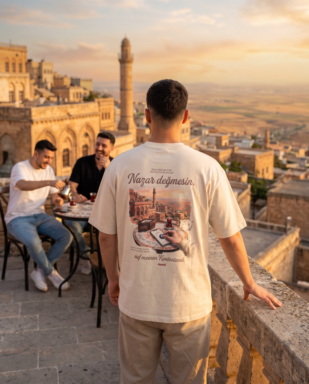 Mann im demli Nazar değmesin. Shirt in Sand von hinten auf einer Terrasse in Mardin