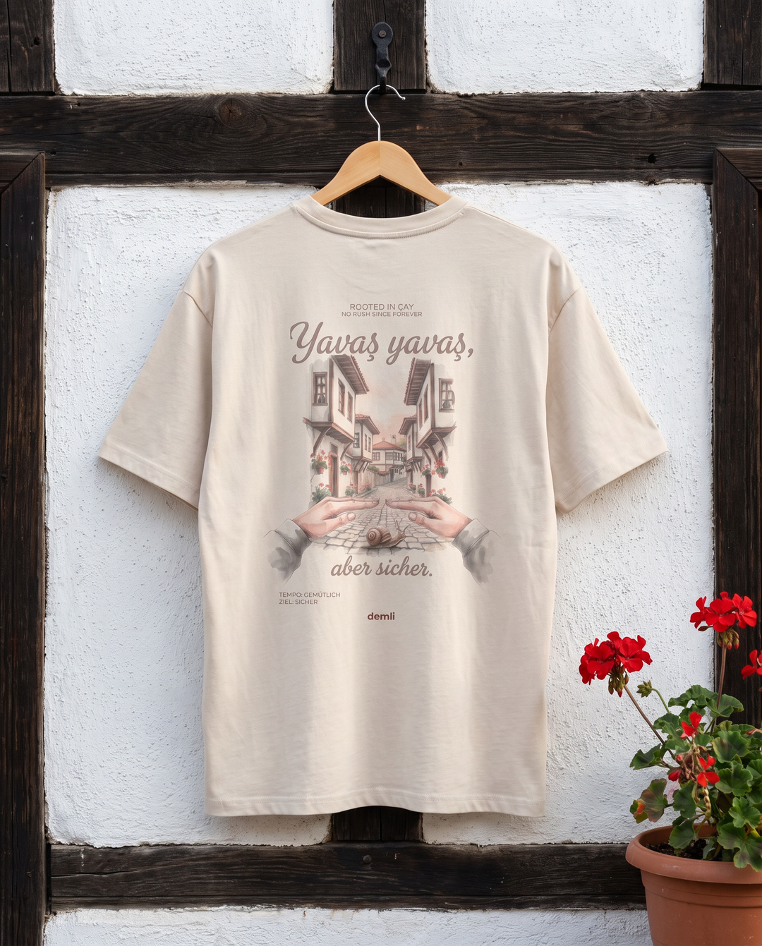 demli Yavaş yavaş Oversized T-Shirt in Sand auf einem Holzbügel an einer Fachwerkwand in Safranbolu