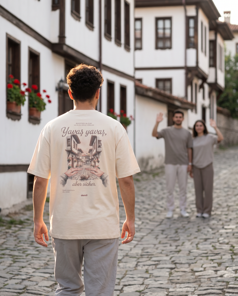Mann im demli Yavaş yavaş Shirt in Sand von hinten in einer Kopfsteingasse in Safranbolu