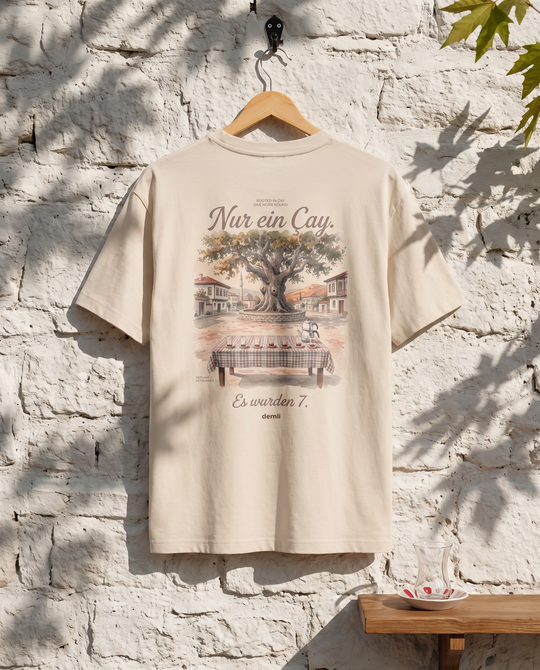 demli Nur ein Çay. Oversized T-Shirt in Sand auf einem Holzbügel an einer Steinwand im Teehaus