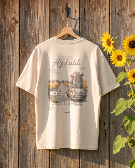 demli Az kaldı. Oversized T-Shirt in Sand auf einem Holzbügel an einer Scheunenwand mit Sonnenblumen